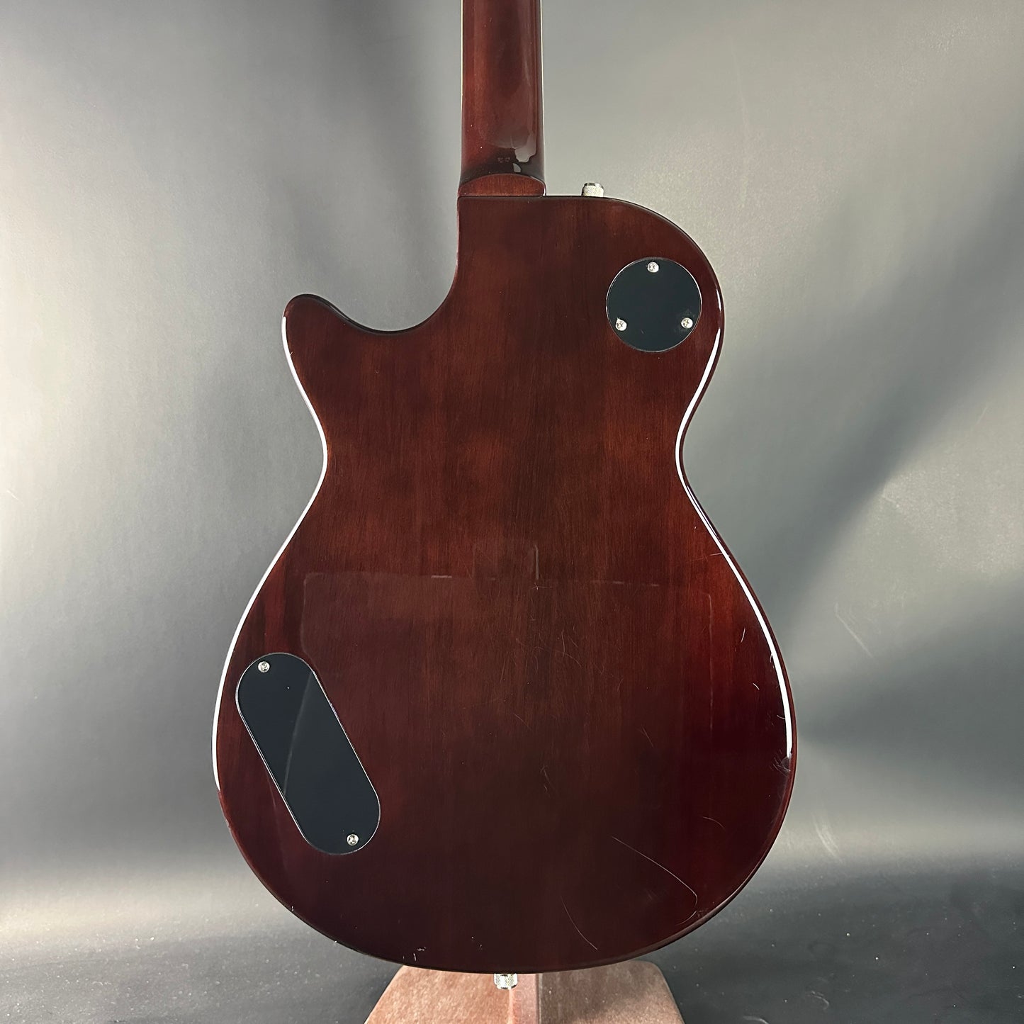 Back view of a brown electric guitar on a gray background