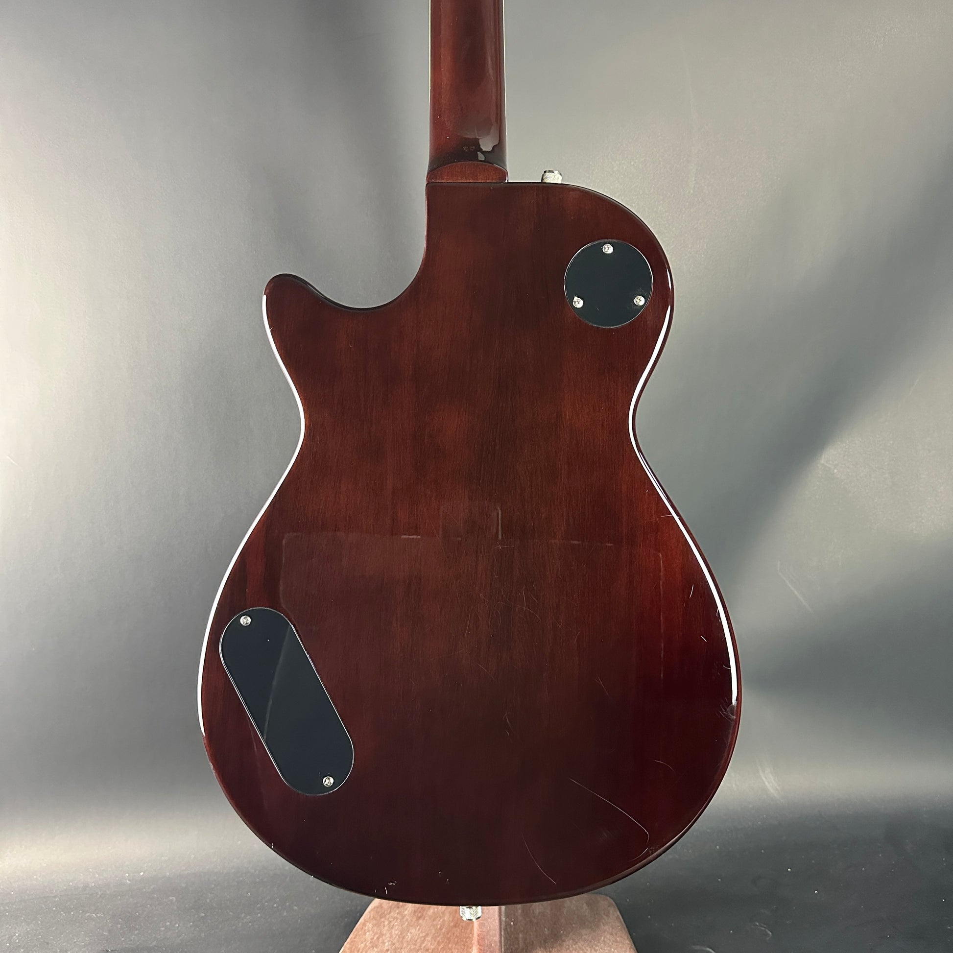 Back view of a brown electric guitar on a gray background