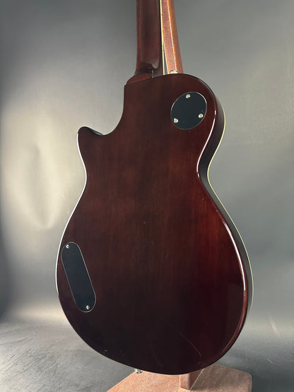 Close-up of a dark brown electric guitar on a gray background