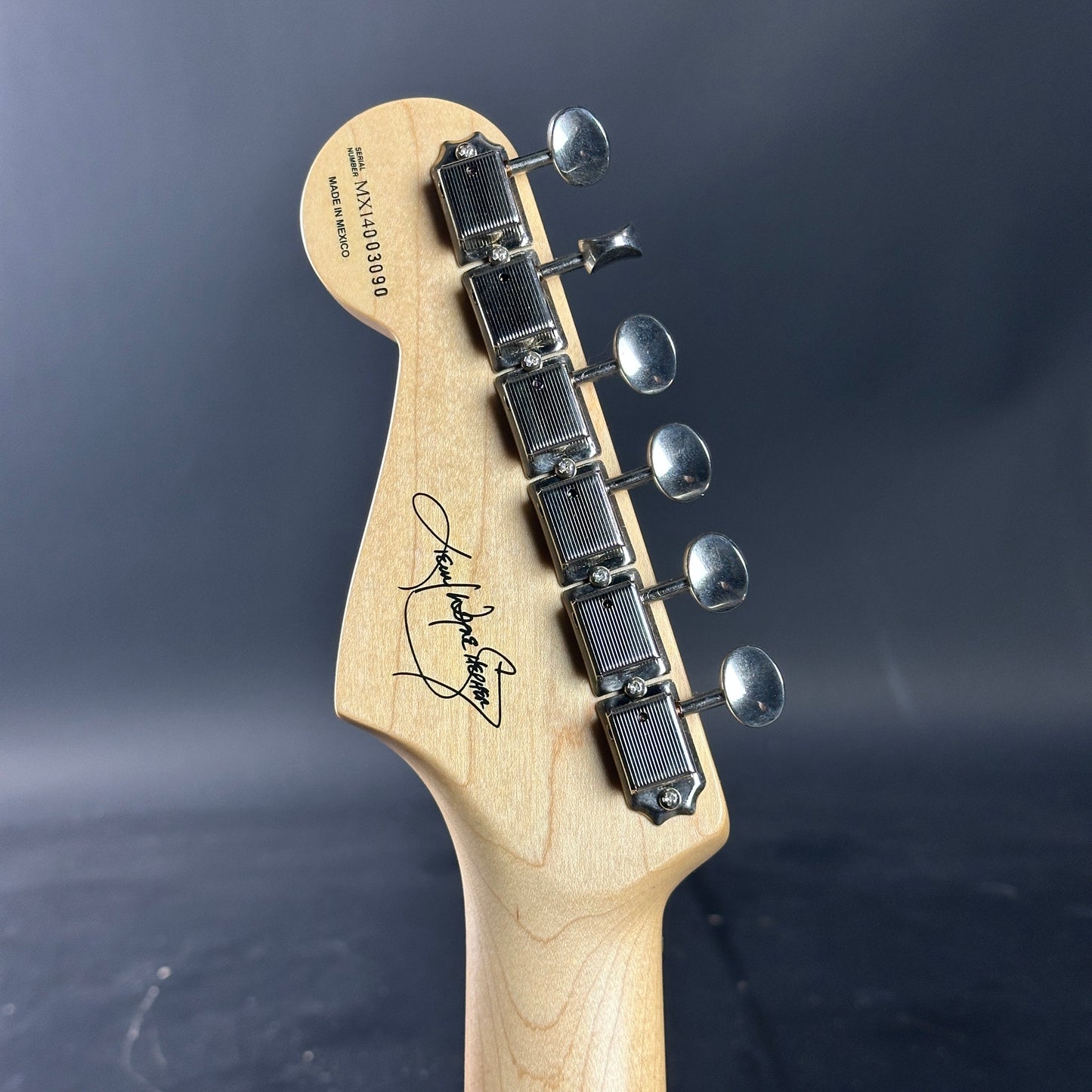 Guitar headstock with tuning pegs on a dark background
