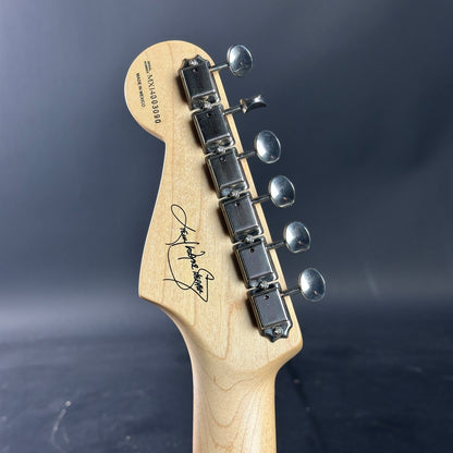 Guitar headstock with tuning pegs on a dark background