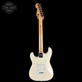 Fender electric guitar shown from the back, featuring a cream-colored body, a natural wood neck, and black hardware, set against a solid black background with a Tone Shop watermark in the top left corner.