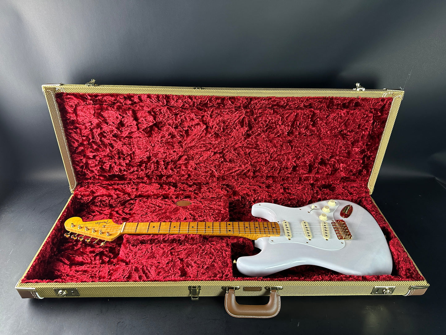 White electric guitar in a red-lined case on a black background