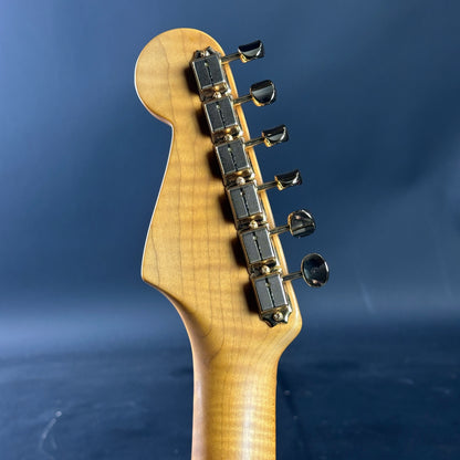 Close-up of a guitar neck with tuning pegs against a blue background