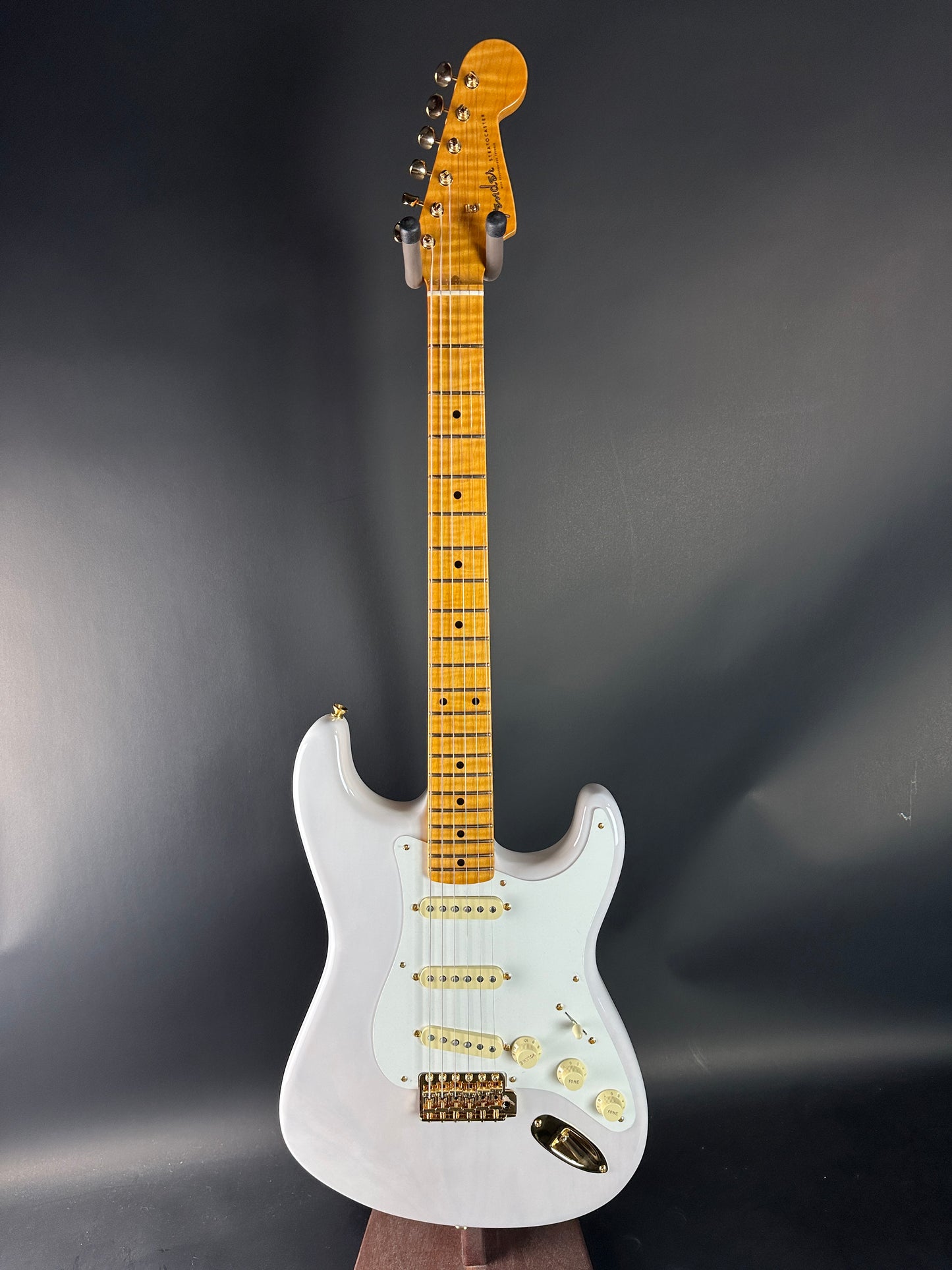 White electric guitar with a wooden fretboard on a dark gray background