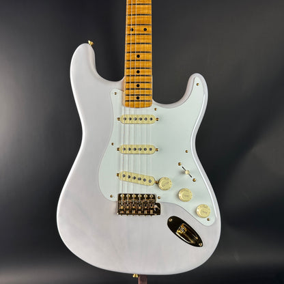 White electric guitar with a wooden fretboard on a dark background