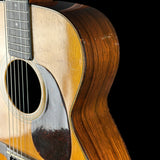 Close-up of an acoustic guitar's soundhole and wooden body on a black background