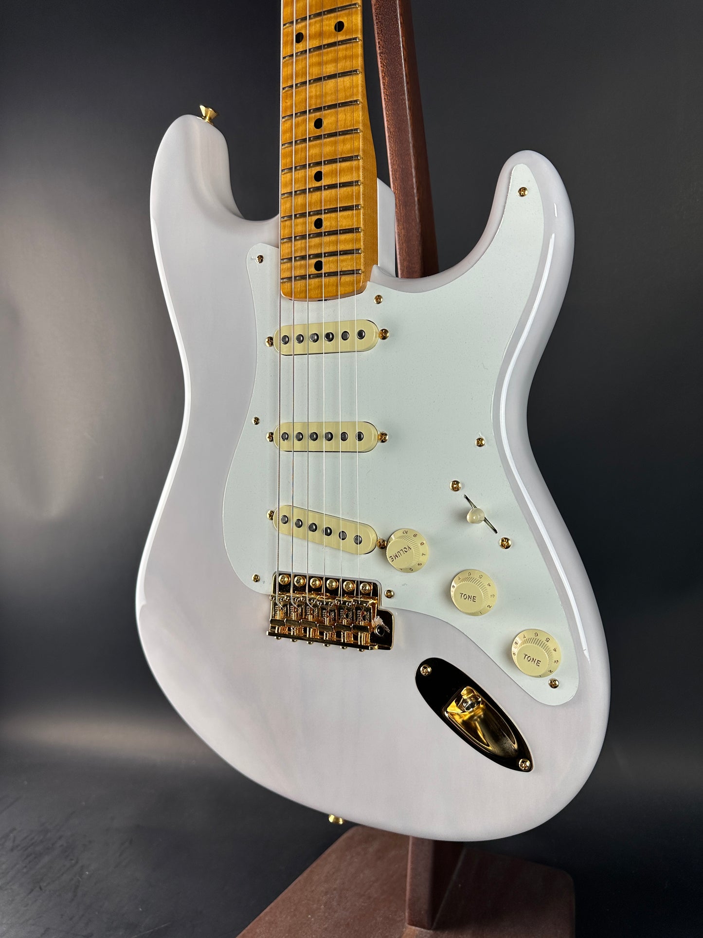 White electric guitar with gold hardware on a dark background