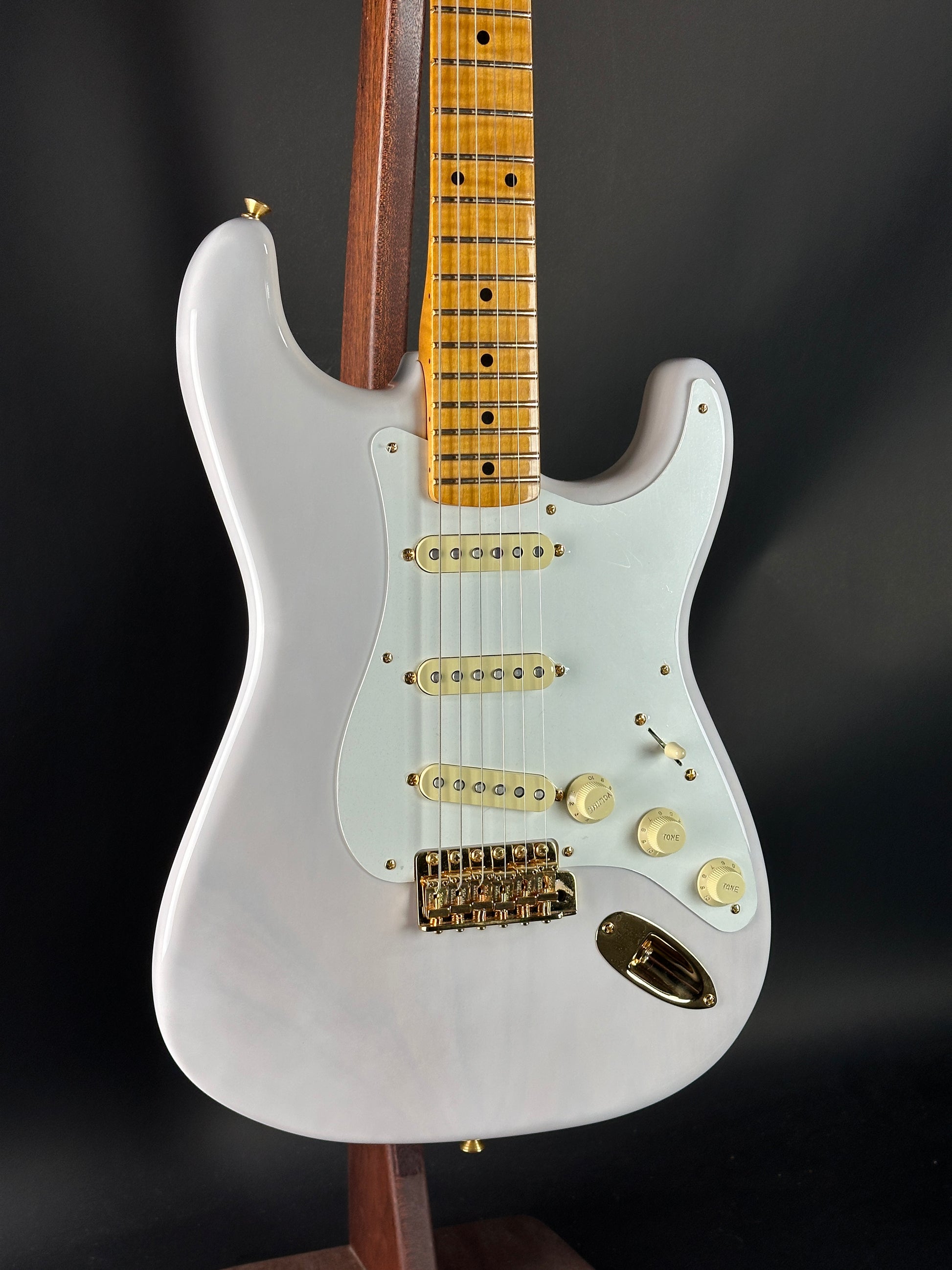 White electric guitar with a wooden fretboard on a black background