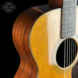 Close-up of an acoustic guitar's body and neck with a black background.