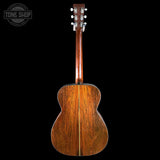 Back view of a wooden acoustic guitar with 'Tone Shop' logo in the corner.