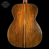 Back view of a wooden acoustic guitar with 'Tone Shop' logo.