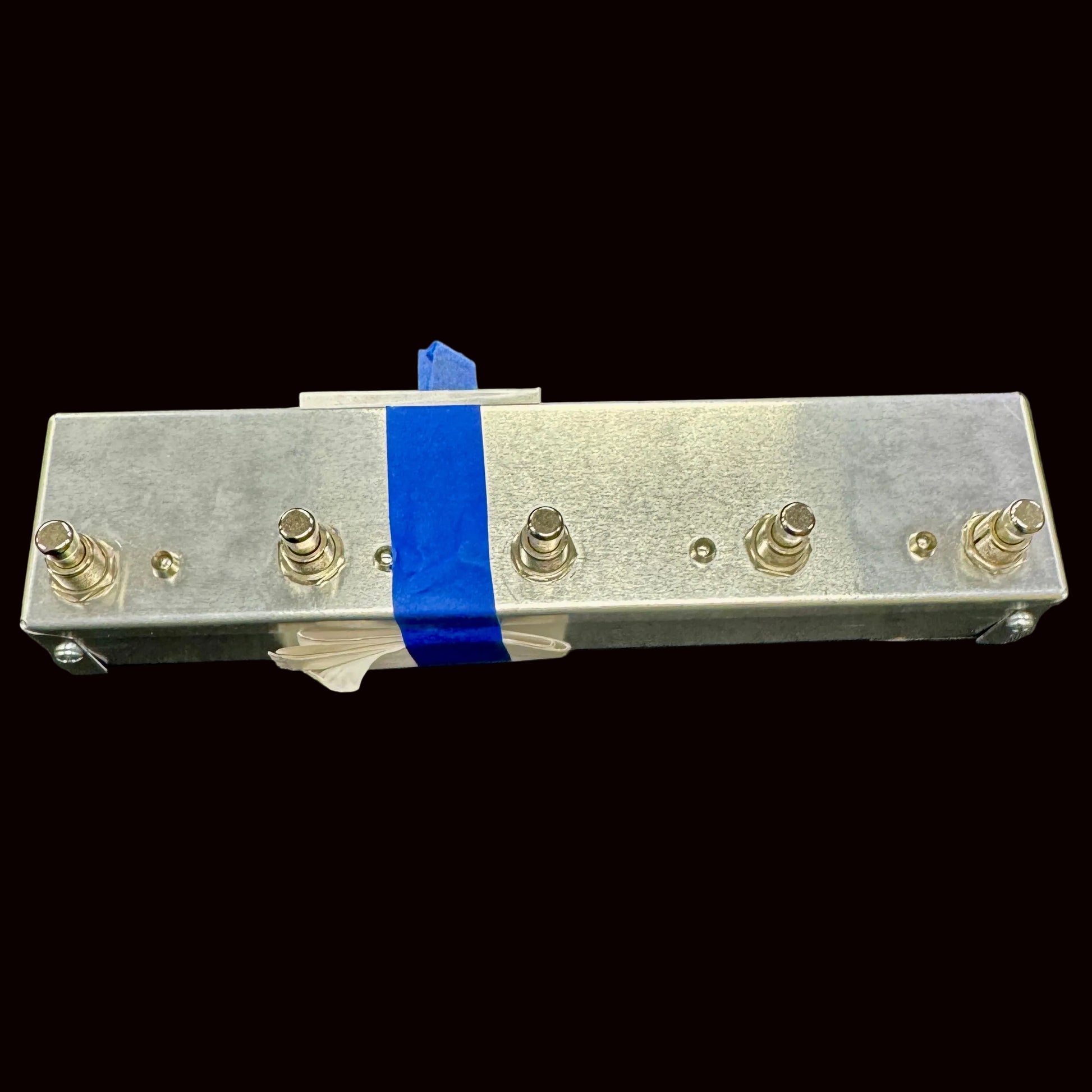 Metal component with screws and blue tape on a gray background