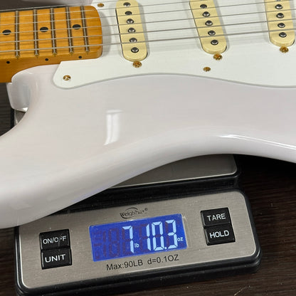 White electric guitar on a digital scale displaying weight