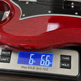 Close-up of a glossy red electric guitar body resting on a digital scale displaying 6.6 lbs.