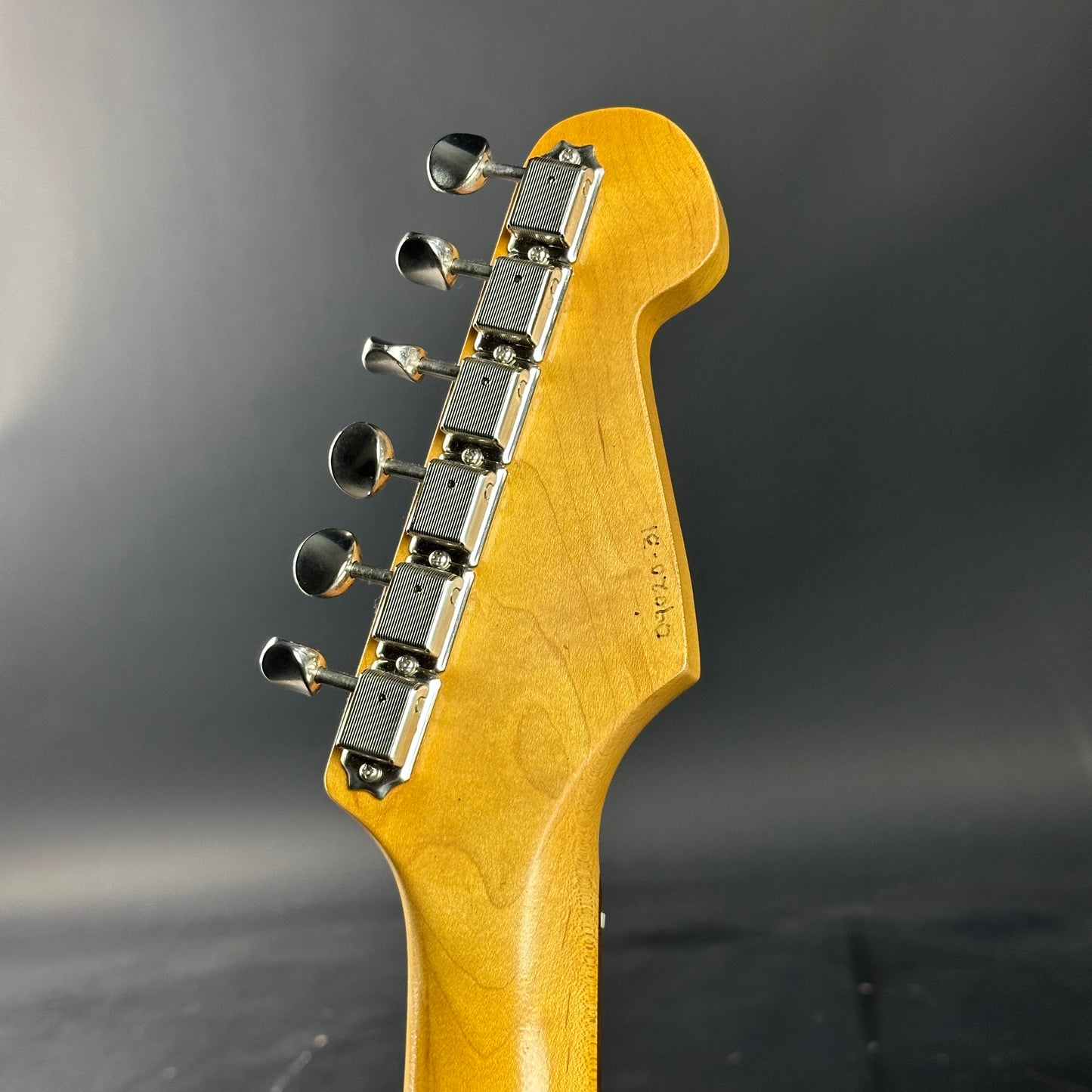 Close-up of a guitar headstock with tuning pegs on a dark background