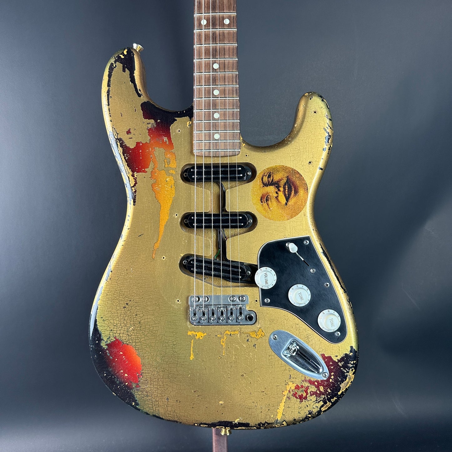 Worn electric guitar with visible wear and tear on a dark background