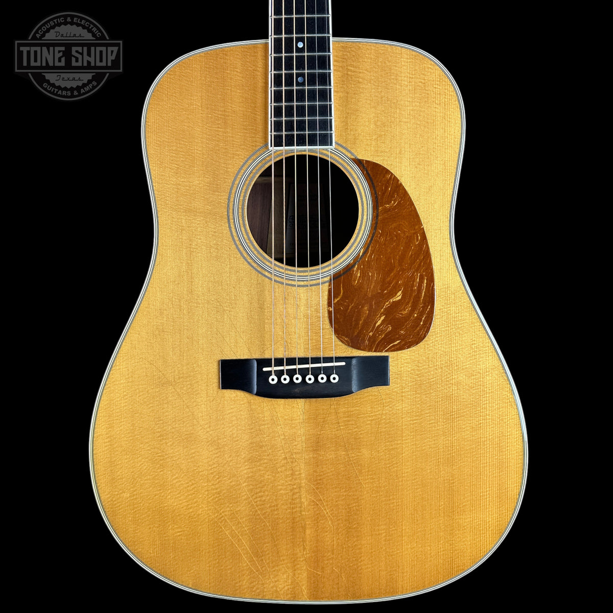 A front-facing acoustic guitar with a natural wood finish and dark fretboard, shown against a solid black background with a Tone Shop watermark in the top-left corner.