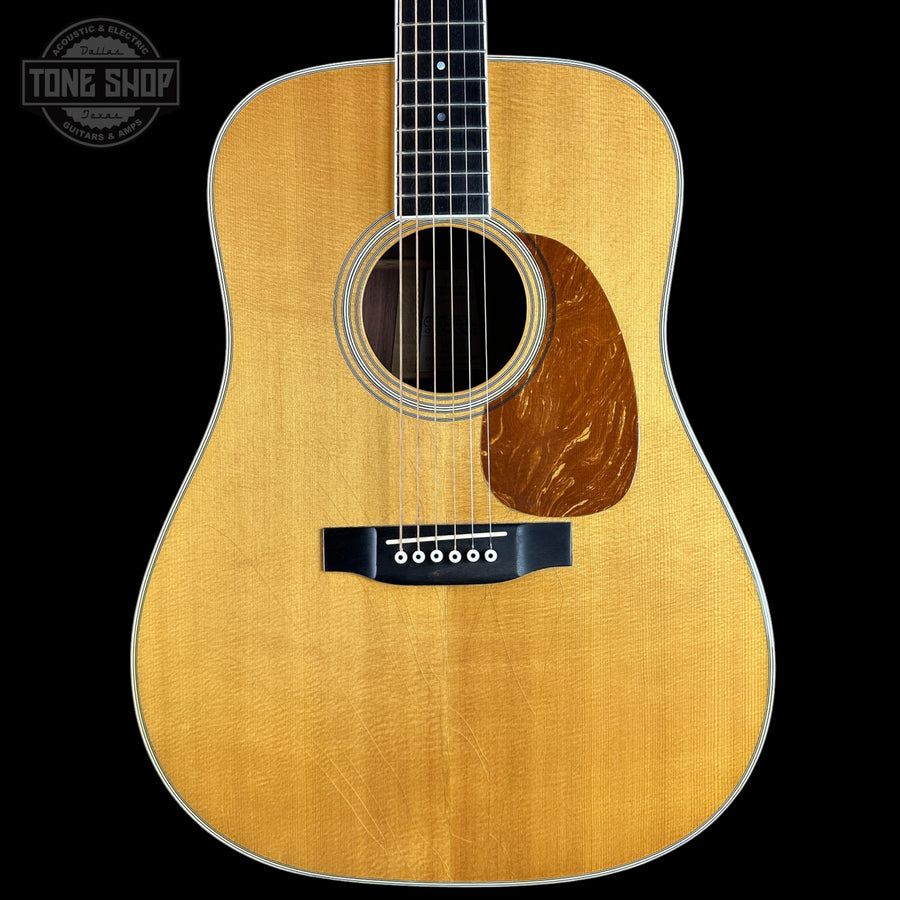 A front-facing acoustic guitar with a natural wood finish and dark fretboard, shown against a solid black background with a Tone Shop watermark in the top-left corner.
