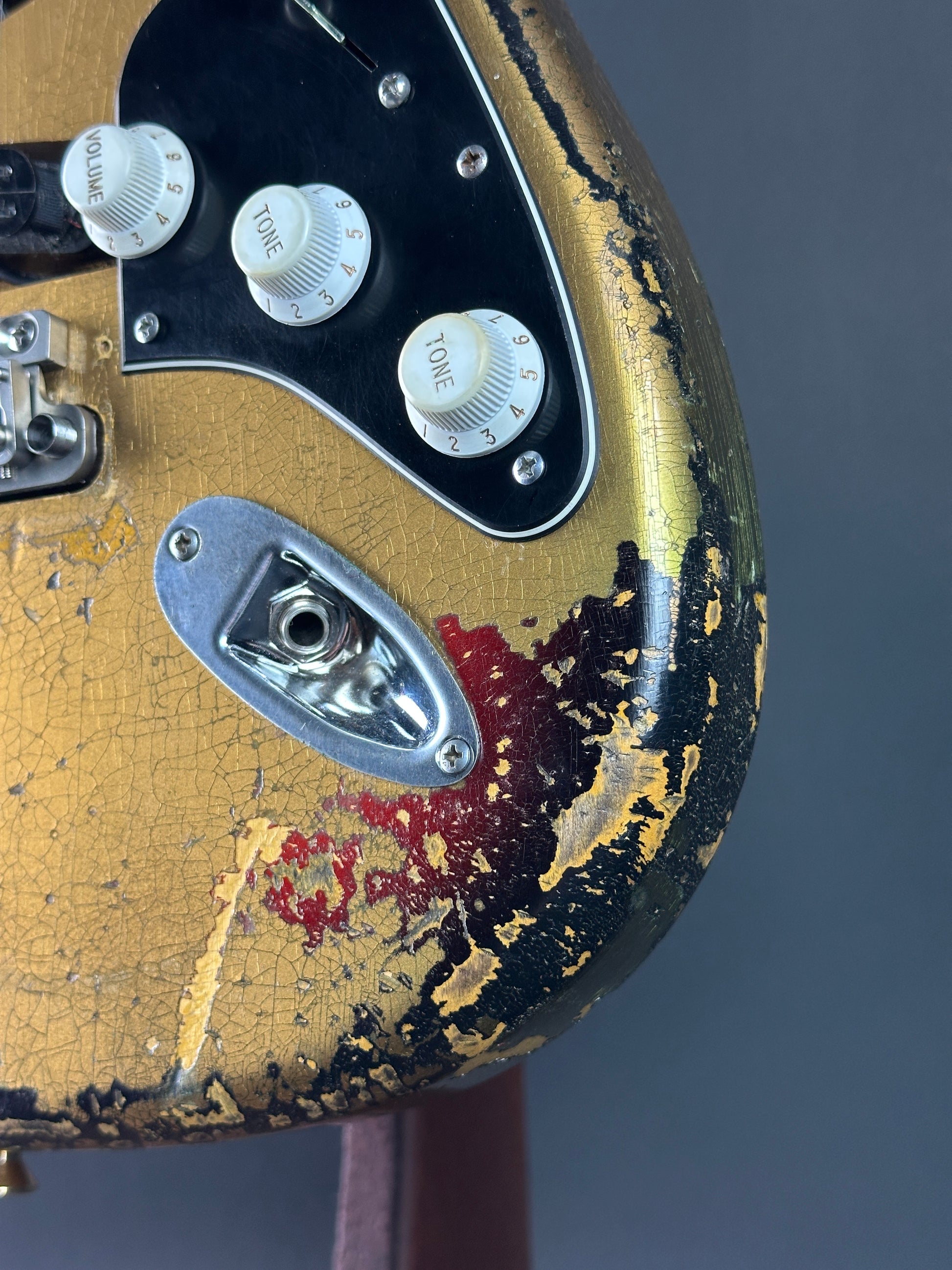 Close-up of a worn guitar pickguard with visible signs of aging and damage.