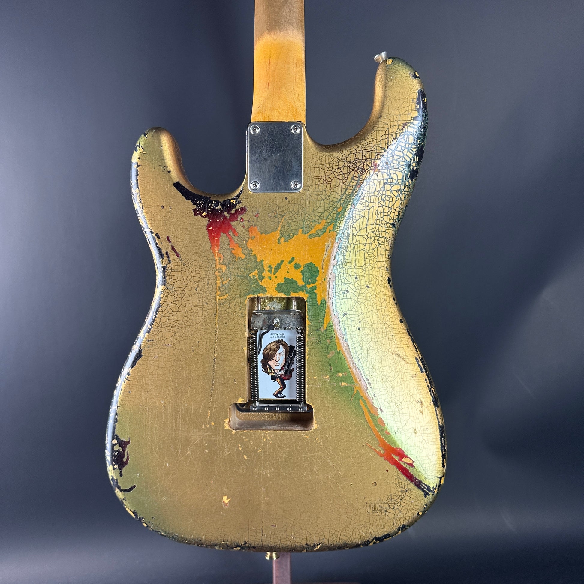 Distressed electric guitar with a colorful design on a dark background