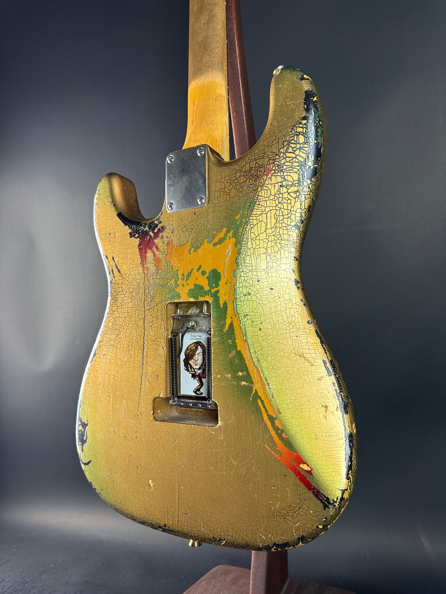 Vintage electric guitar with a worn, multicolored finish on a dark background