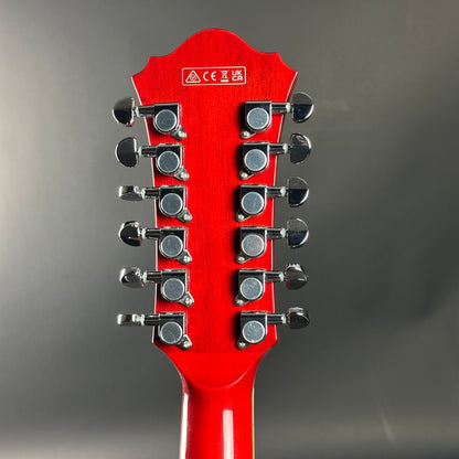 Red guitar headstock with tuning pegs on a gray background