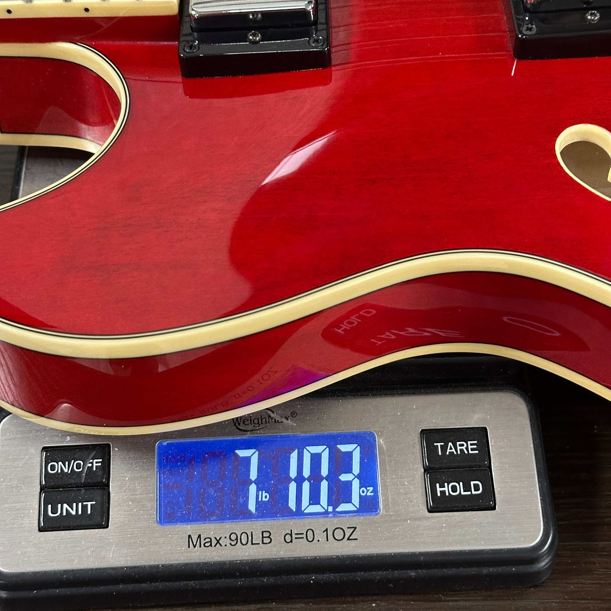 Red electric guitar on a digital scale displaying weight