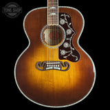 A vintage-style acoustic guitar with a sunburst finish, featuring floral inlay on the pickguard and a decorative trapezoid soundhole rosette, shown against a solid black background.
