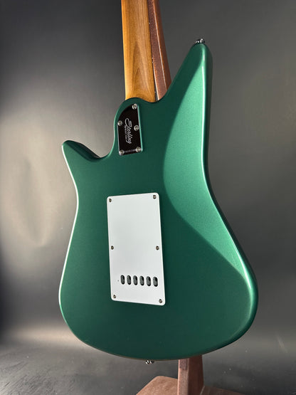 Green electric guitar with a wooden neck on a gray background