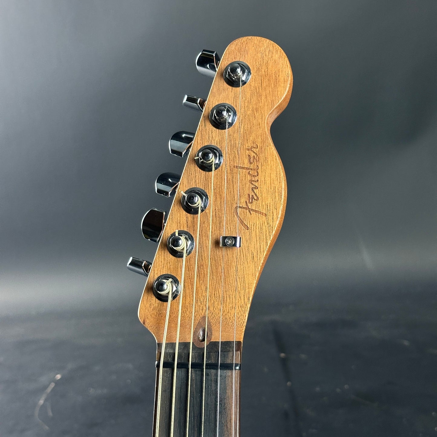 Guitar headstock with Fender logo on a dark background