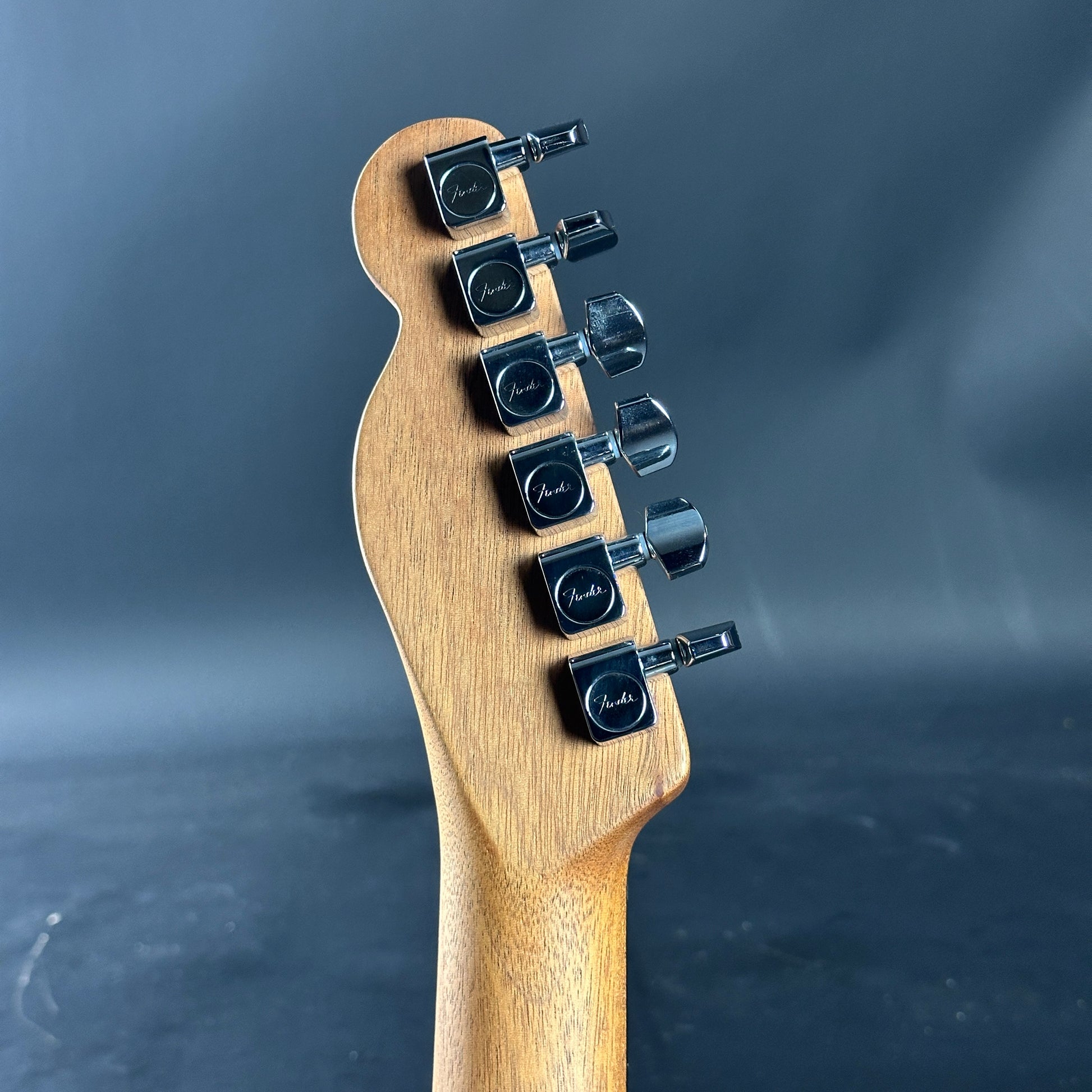 Guitar headstock with tuning pegs on a dark background