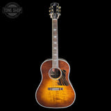A vintage-style acoustic guitar with a sunburst finish, shown vertically against a solid black background. The brand 'Gibson' is visible on the headstock.