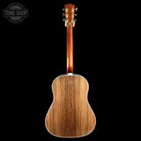 The back of an acoustic guitar with a natural wood grain finish, shown against a solid black background with a Tone Shop watermark in the top left corner.