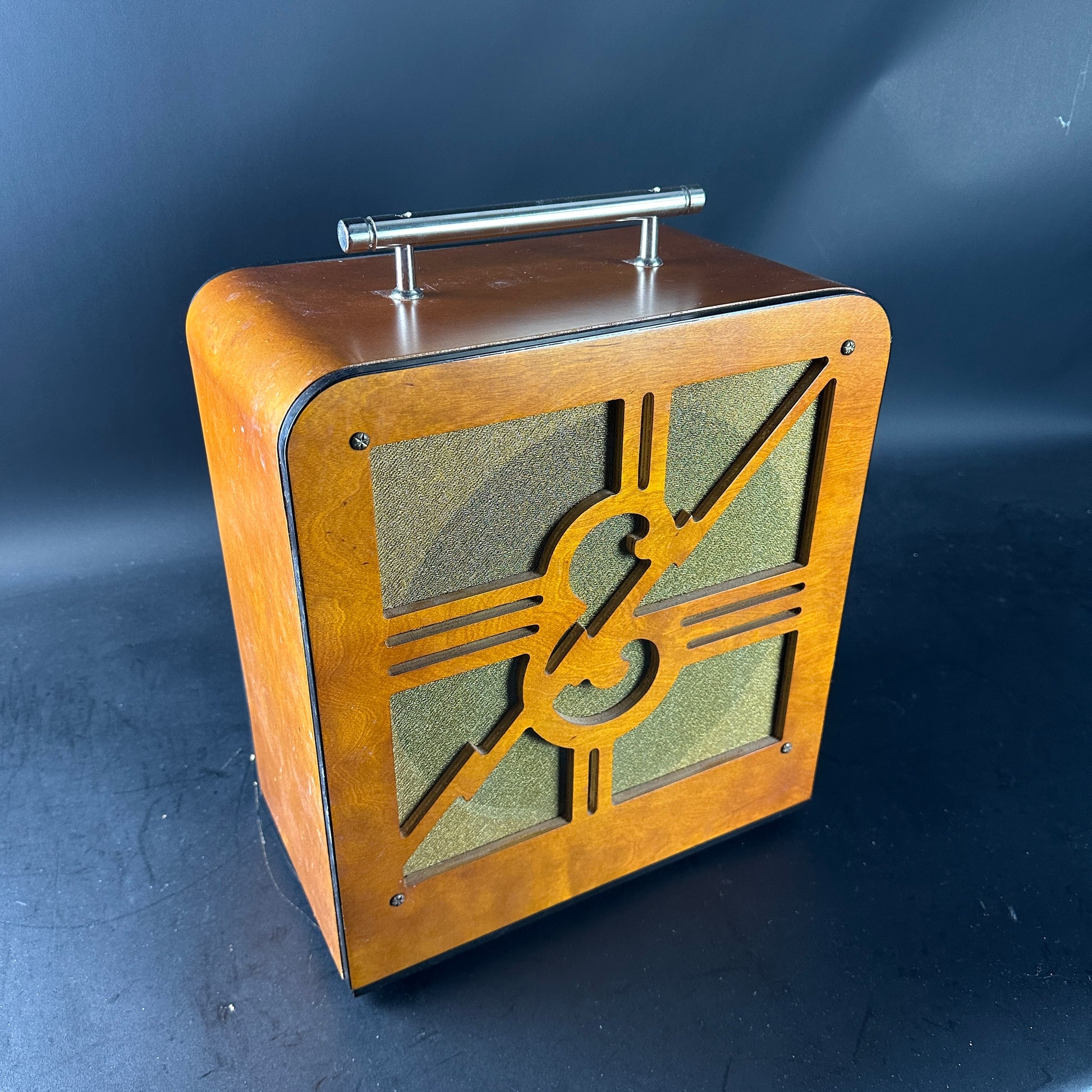 Wooden speaker with decorative emblem on a dark background