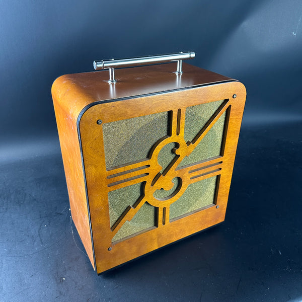Wooden speaker with decorative emblem on a dark background