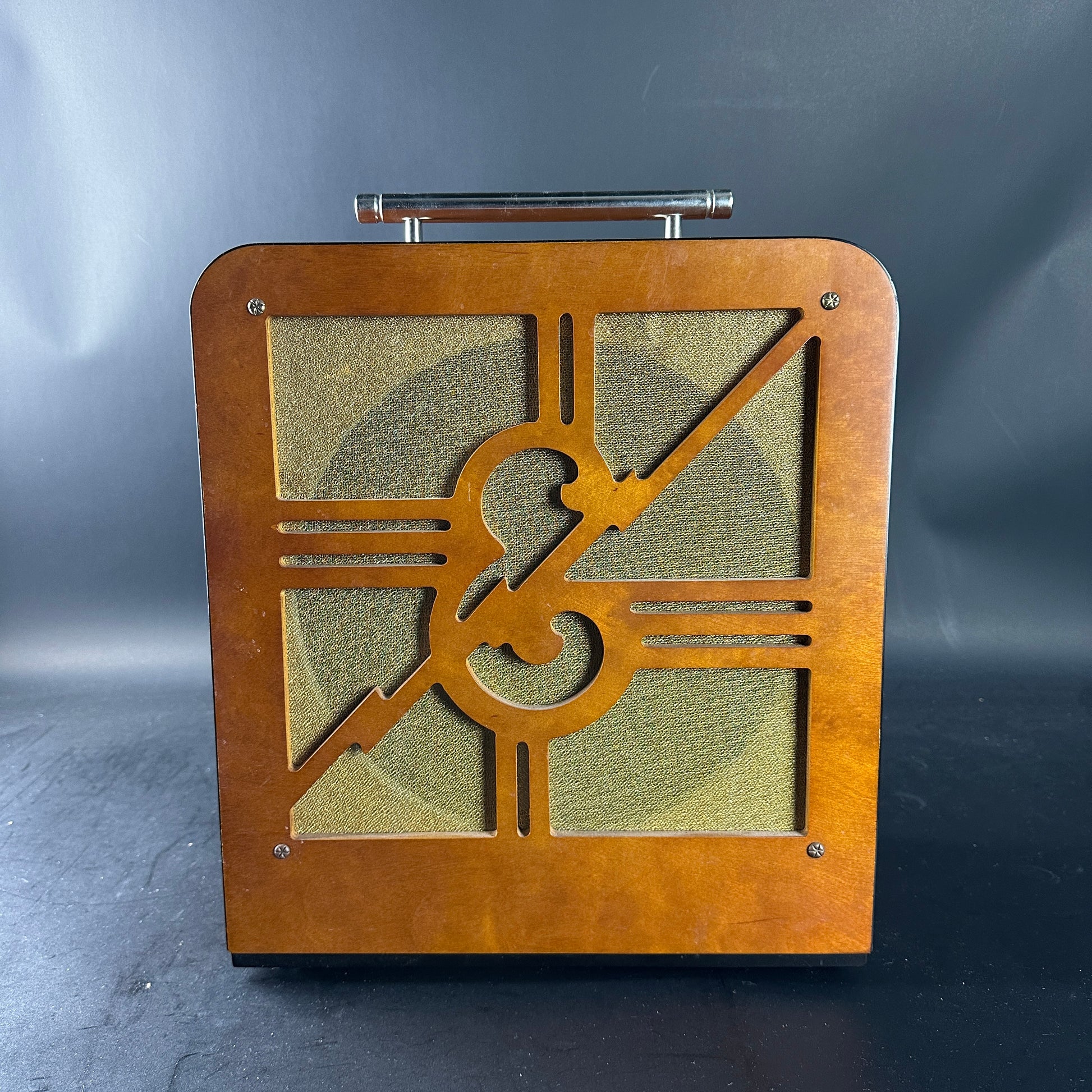 Wooden speaker with treble clef design on a dark background