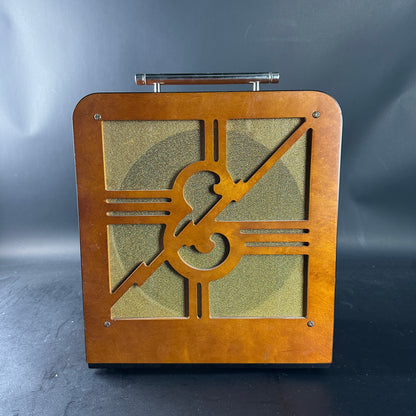 Wooden speaker with treble clef design on a dark background