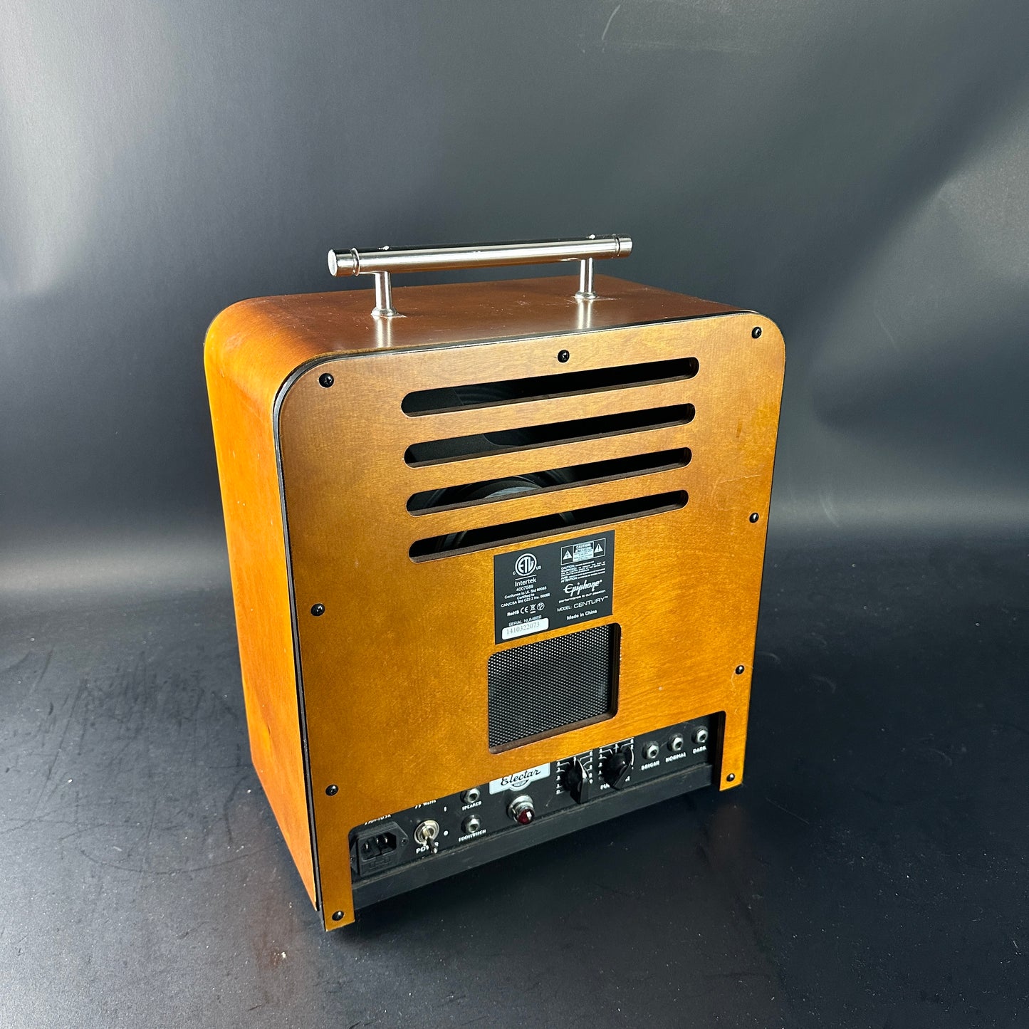 Wooden speaker with metal handle on a dark background