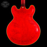 The back of a red electric guitar body with a glossy finish and a yellow binding edge, shown against a black background with a Tone Shop watermark in the top left.