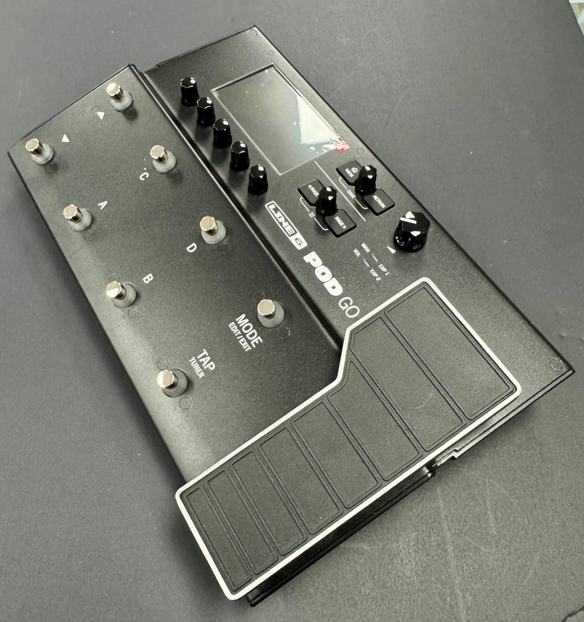 Black guitar effects pedal with multiple knobs and a footswitch on a gray background