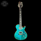 A turquoise blue electric guitar with a flamed maple top and dark fretboard, shown against a solid black background. A Tone Shop watermark is visible in the top-left corner.