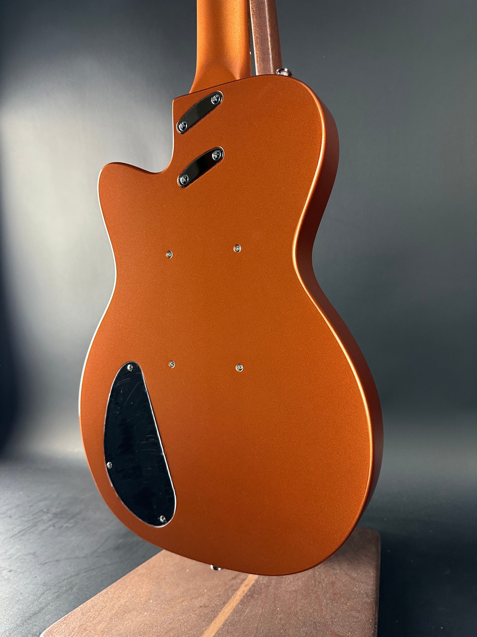 Close-up of a brown electric guitar body on a dark background