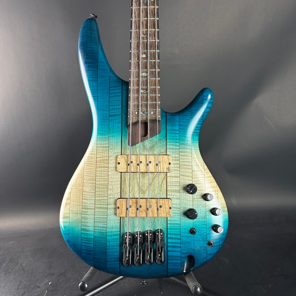 Blue and green electric bass guitar on a gray background