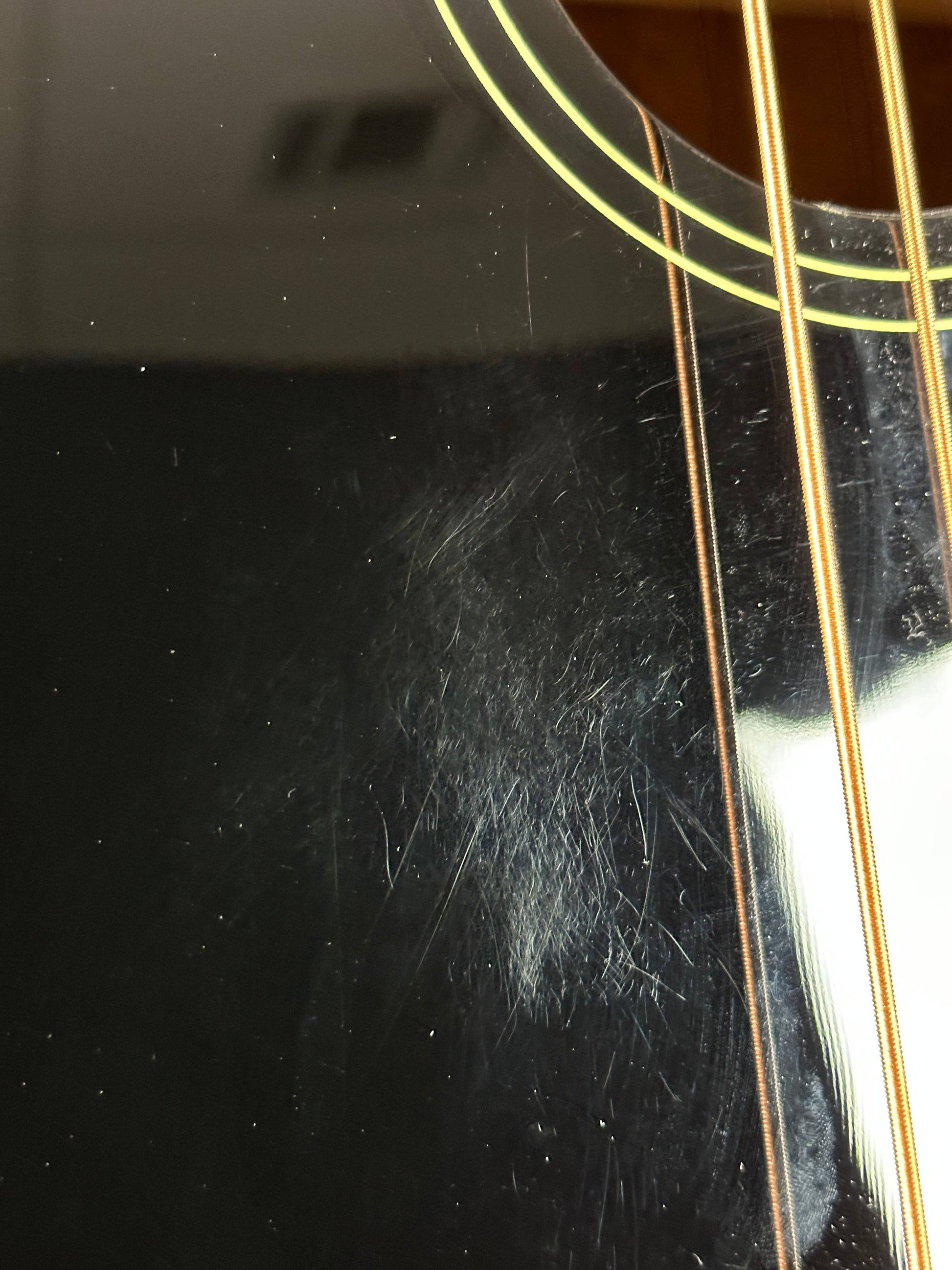 Close-up of a black acoustic guitar with visible strings and wood texture.