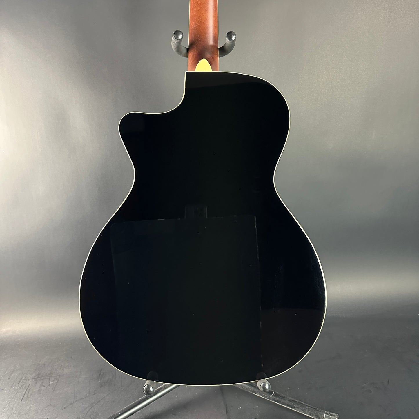 Black acoustic guitar on a stand against a gray background