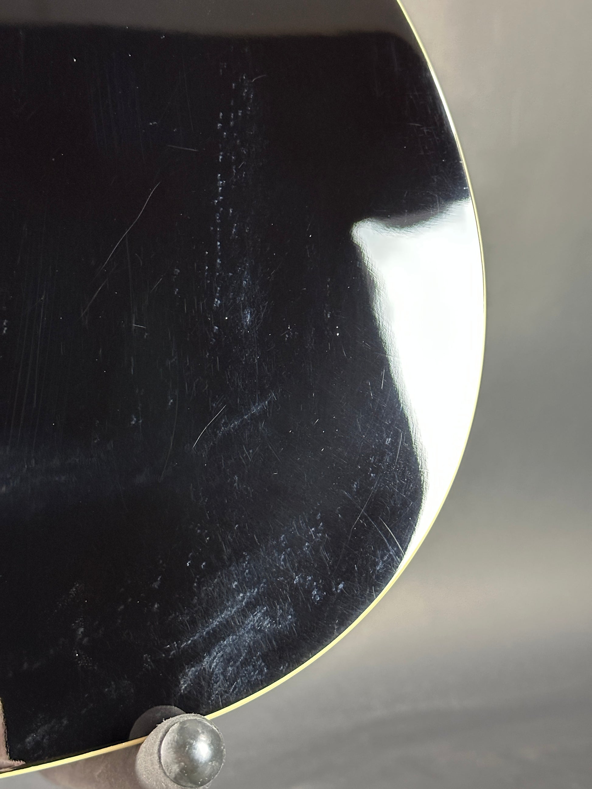 Close-up of a black guitar pickguard with a silver screw on a blurred background