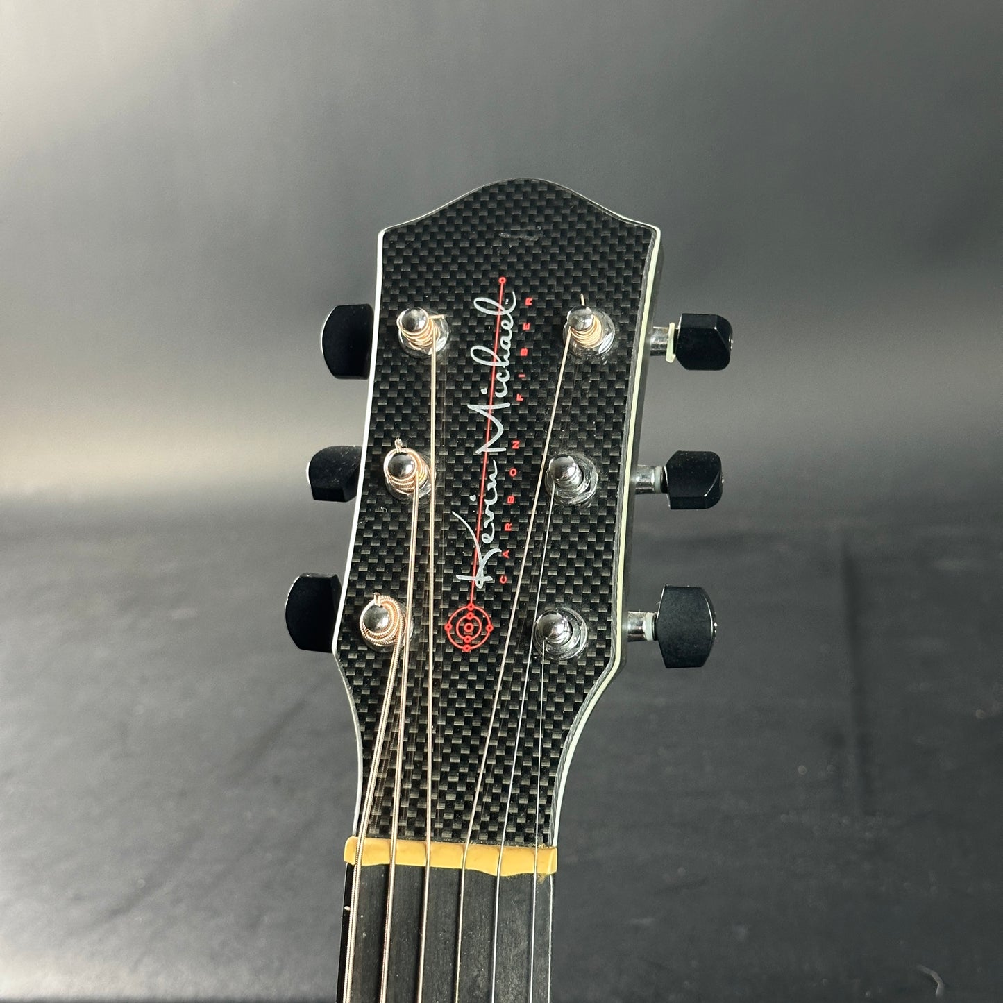 Guitar headstock with brand logo on a gray background
