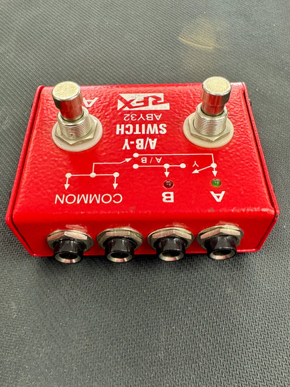 Red switch box with two toggle switches and four socket ports on a gray surface