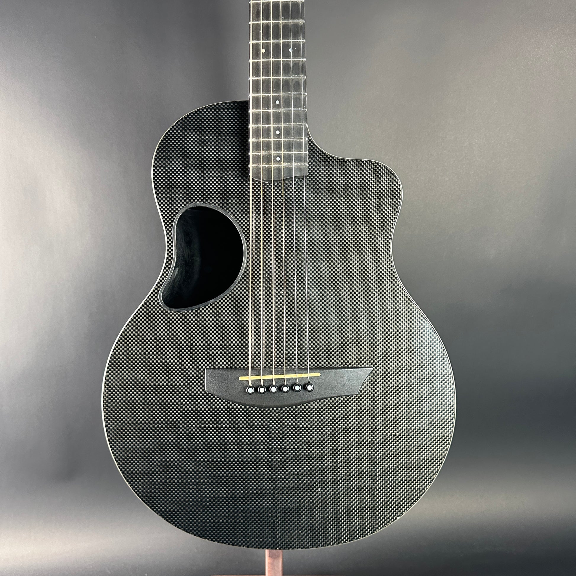 Carbon fiber acoustic guitar on a stand with a gray background